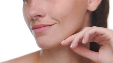 Young woman with fair skin freckles strokes jawline revitalized