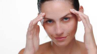 Brunette latina with freckles touches face moisturized skin