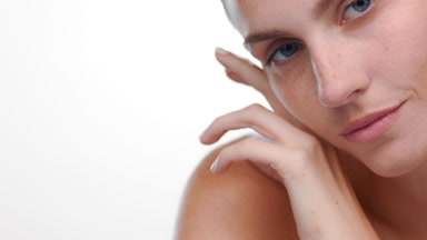 Spanish woman with freckles caresses jawline soft skin