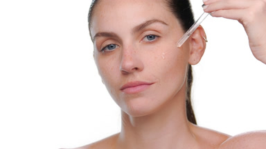 Light-skinned latina with freckles applies face serum