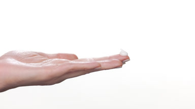 Fair-skinned hand with heap of cream on finger white background