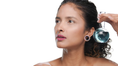 Light brown-skinned woman holds small blue flask near her face