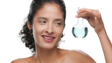 Young latin woman with curly hair watches small blue flask white
