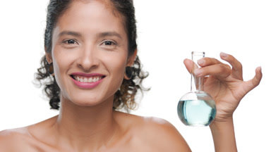 Light brown-skin latina holds round blue flask looks at camera