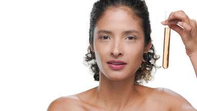Off-shoulder hispanic woman holds test tube with orange liquid