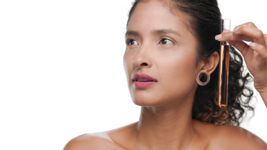 Latin model dark curls moves orange test tube along her face