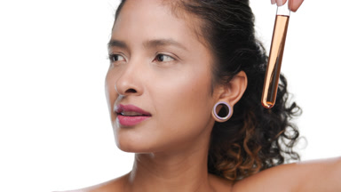 Attractive hispanic woman holds orange test tube over face white