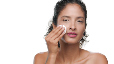 Curly black-haired woman uses cotton pad isolated on white