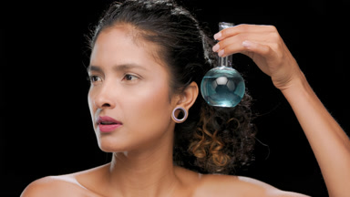 Hispanic woman holds blue flask near face uncovered shoulders