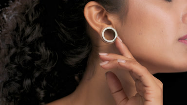 Latin american woman slides finger over jawline black background