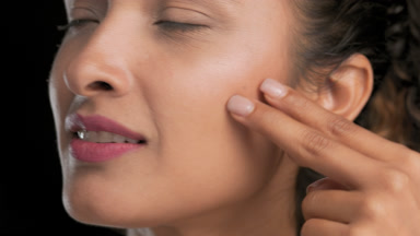 Brown-eyed woman strokes under eye area with two fingers