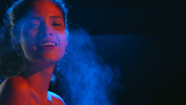 Latin american woman in red-blue sprays blue fragrance on black
