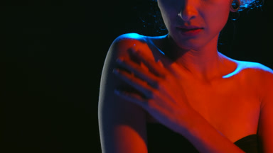 Elegant hispanic woman in blue-red light strokes shoulder