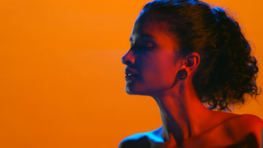Beauty latin woman in red and blue led touches chin turns