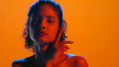 Attractive latin woman in blue and red gel light touches chin