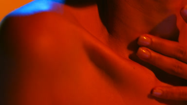 Young woman in blue and red light strokes neck hollow orange bg