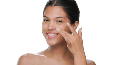 Brown-haired model touches under-eye smiles fresh skin