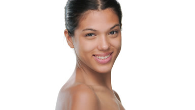 Tanned beauty smiles over shoulder shows moisturized skin