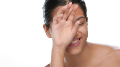 Young woman laughs covers eye clear skin showcased