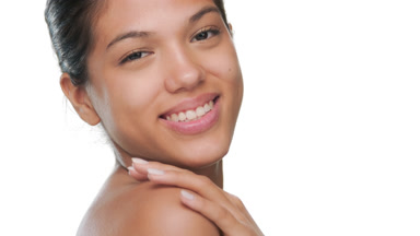 Happy model smiles over shoulder strokes soft skin
