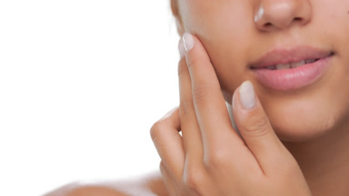Beauty model slides fingers up cheek smooth skin
