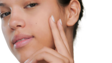 Young model touches cheek presenting clear skin
