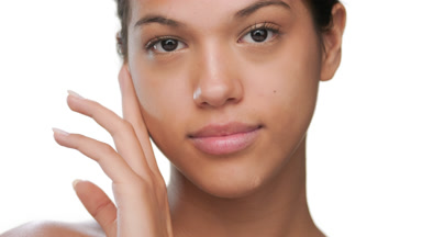 Cosmetic model touches cheek to show balanced skin