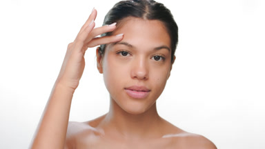 Young beauty touches forehead demonstrates skin clearness