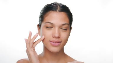 Skin care model touches cheek smiles clean skin shown