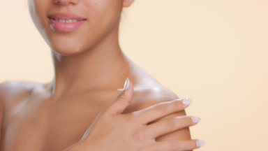 Young female strokes shoulder looks at camera soft skin