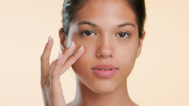 Young woman slightly touches cheek showing clear skin