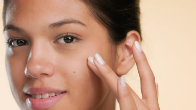 Young skin care model gently touching under eye pure skin