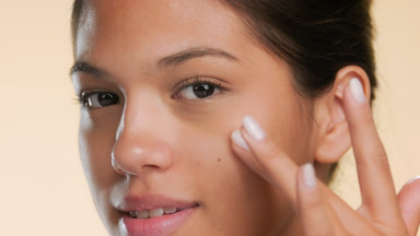 Model touches cheek under eye smiles shows soft skin