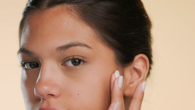 Young beauty slides finger up cheek shows soft skin