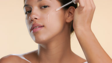 Skincare model applies face serum on her cheek