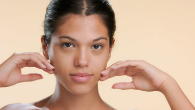 Youthful woman touches chin with backs of both hands