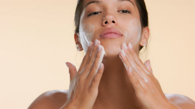 Young woman washing face with cleansing foam