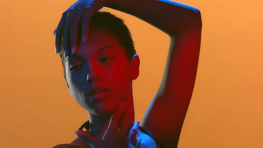 Beauty model in red blue light turns head hand on hair