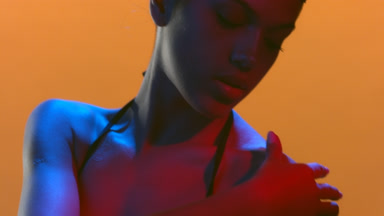 Elegant model in blue red gel light touches shoulder