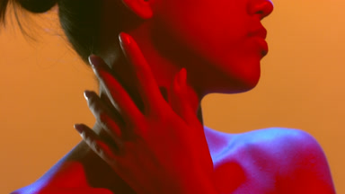 Sensual model in blue red led touches nape looks aside