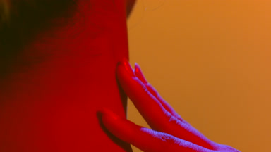 Woman in red light gently touching her neck skin