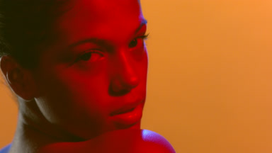 Model in red gel light turns head looks over shoulder