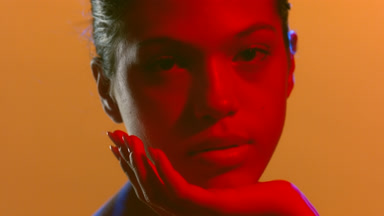 Cosmetic model in red light supports head with her palm