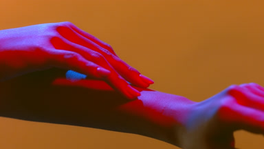 Female hands in blue-red light caressing each other