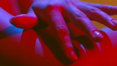 Female hands in red-blue gel light touch arm skin