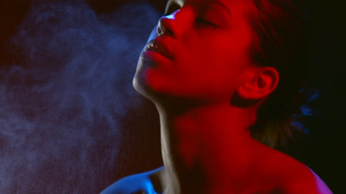 Model in red led light sprays scent and inhales aroma