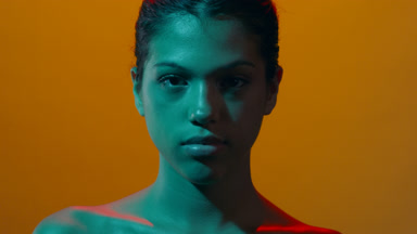 Model in cyan gel light opens eyes looks at camera