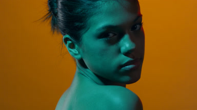 Young female model in red & cyan led looks over shoulder