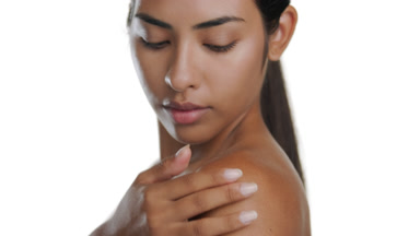Young Latin woman stroking shoulder, presenting moisturized skin