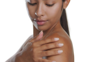 Young Latina stroking shoulder, demonstrating soft, smooth skin